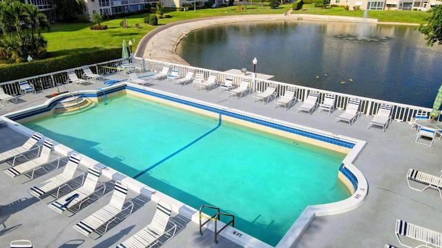 view of pool featuring a lawn, a patio area, and a water view