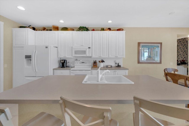 kitchen featuring white appliances, white cabinets, and a kitchen breakfast bar