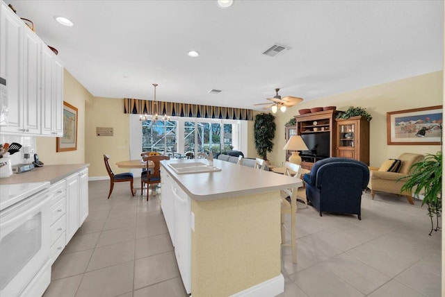 kitchen with an island with sink, pendant lighting, sink, white range with electric cooktop, and ceiling fan with notable chandelier