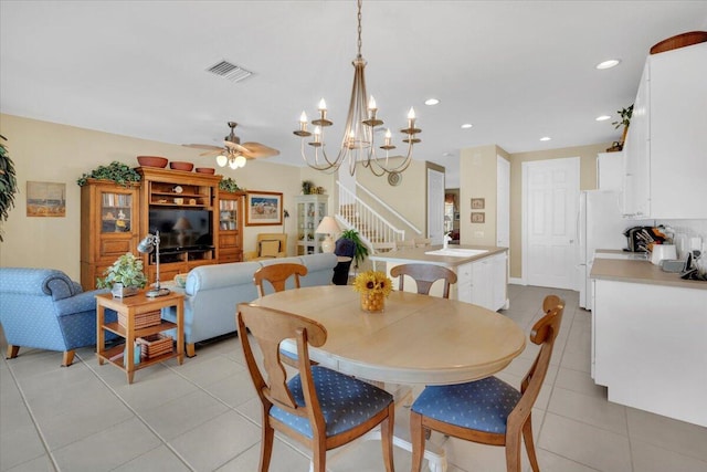 dining space with ceiling fan with notable chandelier, sink, and light tile floors