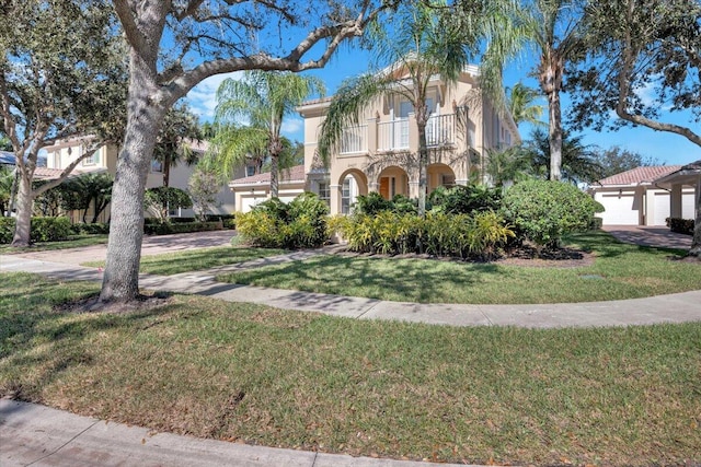 mediterranean / spanish home with a front lawn, a balcony, and a garage