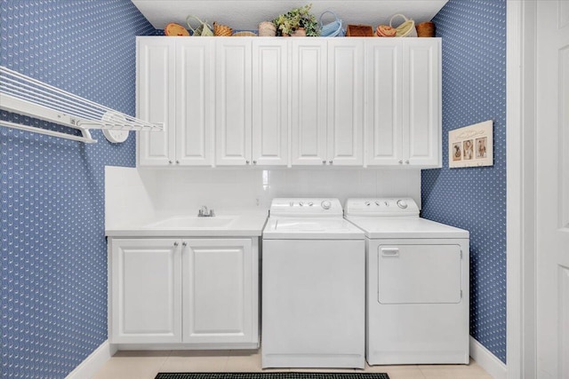 laundry area featuring washing machine and clothes dryer, cabinets, sink, and light tile floors