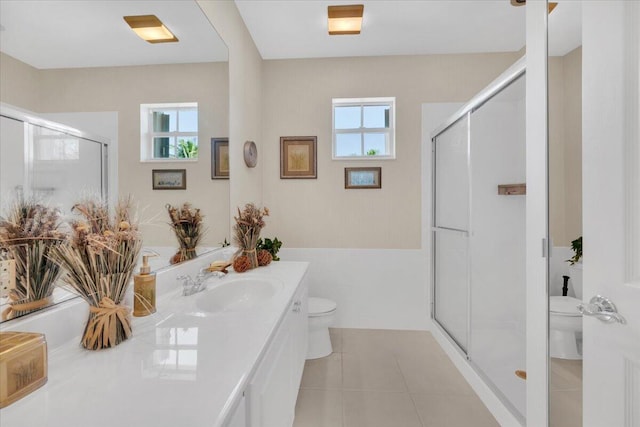 bathroom featuring toilet, tile floors, vanity, and a wealth of natural light