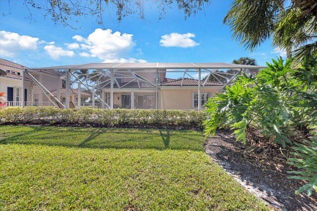 back of house featuring a lanai and a yard