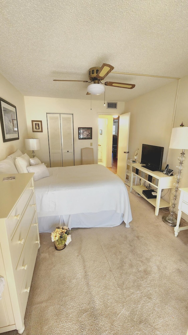 bedroom with a closet, ceiling fan, carpet, and a textured ceiling