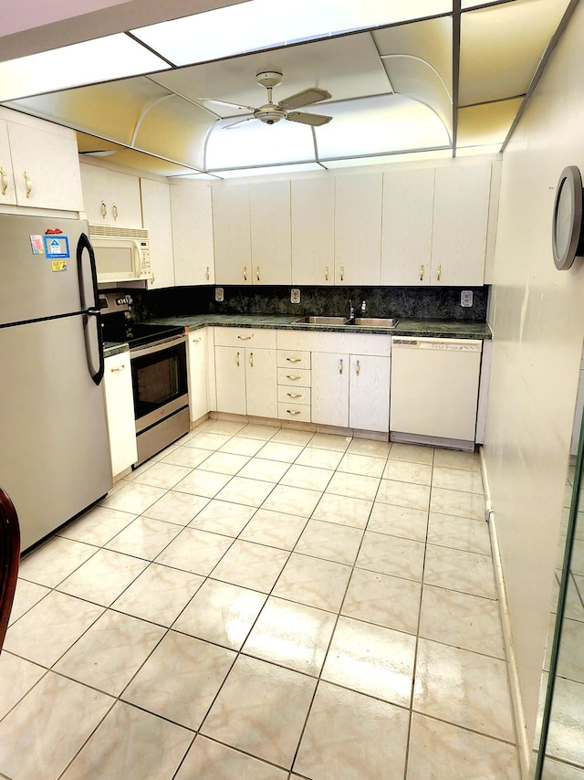 kitchen with light tile patterned flooring, appliances with stainless steel finishes, sink, and white cabinets