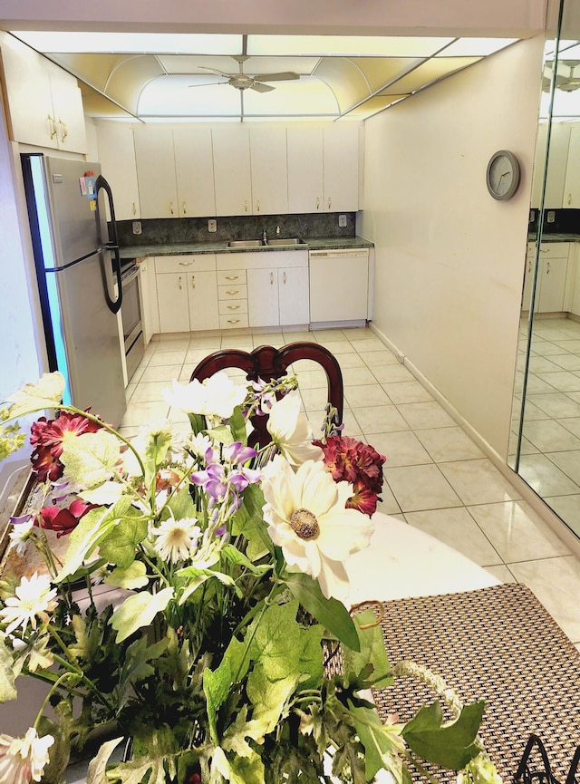 kitchen with light tile patterned floors, stainless steel appliances, sink, and white cabinets