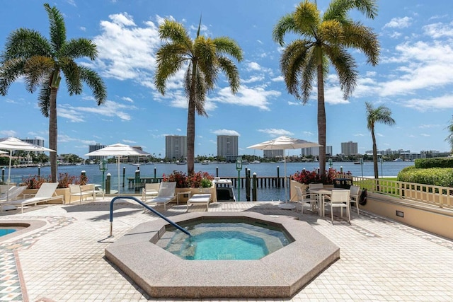 view of pool with a water view, a hot tub, and a patio