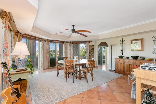 dining area featuring a raised ceiling, ornamental molding, ceiling fan, and light tile floors