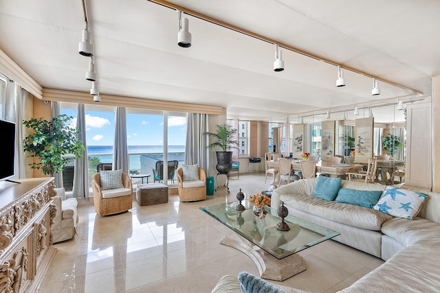 living room featuring rail lighting, a water view, and light tile floors