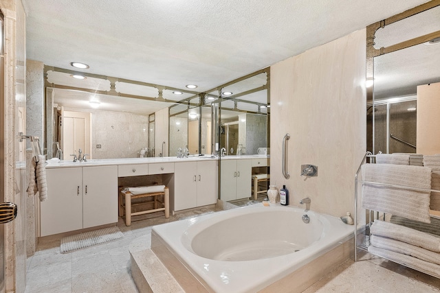 bathroom with a tub, a textured ceiling, tile floors, and dual vanity