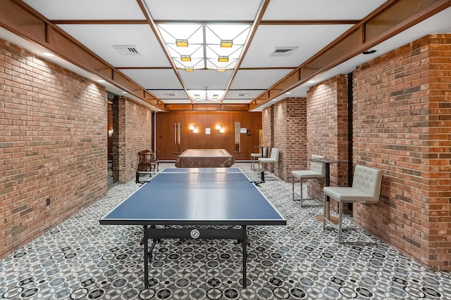 rec room featuring brick wall, dark tile flooring, and wooden walls