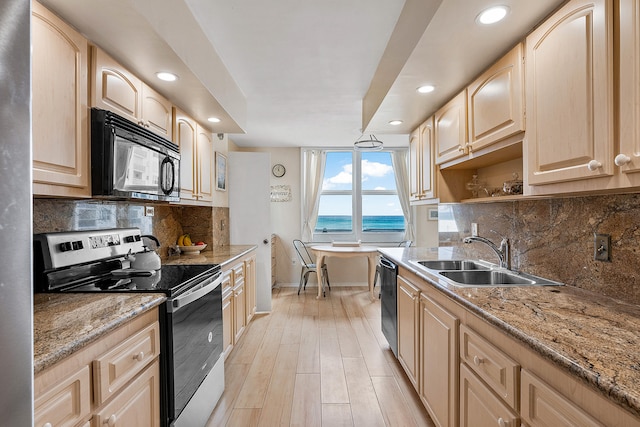 kitchen with backsplash, light stone counters, sink, and black appliances