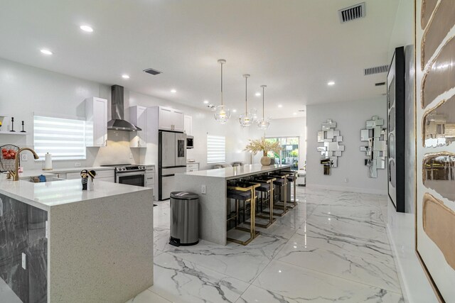 kitchen featuring kitchen peninsula, stainless steel appliances, sink, wall chimney range hood, and white cabinets