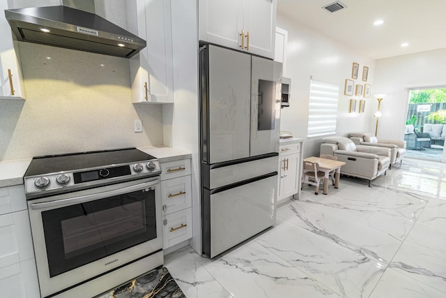 kitchen featuring stainless steel electric range oven, light countertops, visible vents, refrigerator with glass door, and wall chimney exhaust hood