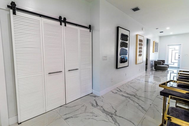 corridor with marble finish floor, visible vents, and a barn door