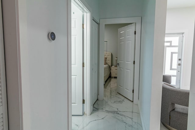 corridor featuring marble finish floor and baseboards