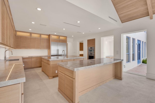 kitchen with light tile flooring, a kitchen island with sink, appliances with stainless steel finishes, light brown cabinets, and sink