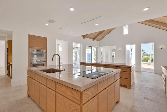 kitchen with a kitchen island with sink, sink, lofted ceiling with beams, double oven, and black electric stovetop