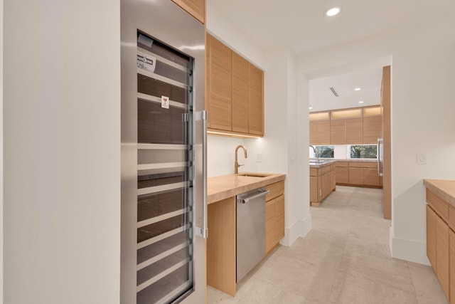 kitchen with light brown cabinetry, light tile floors, appliances with stainless steel finishes, and sink