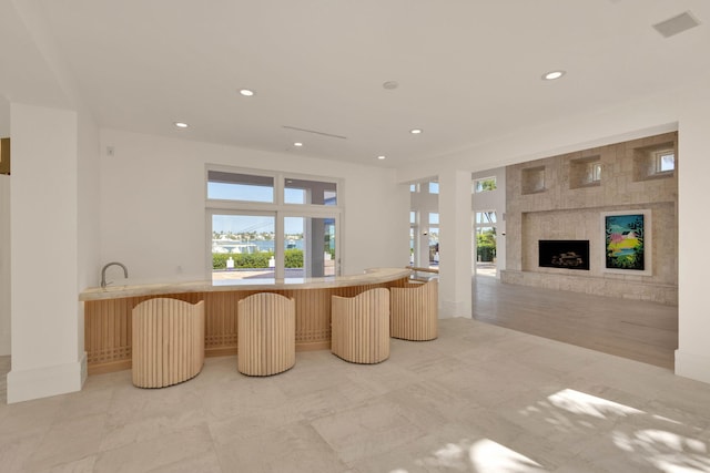 interior space featuring a kitchen bar, a tile fireplace, a center island, and light tile floors