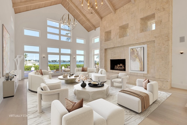 living room with wooden ceiling, high vaulted ceiling, an inviting chandelier, and a fireplace