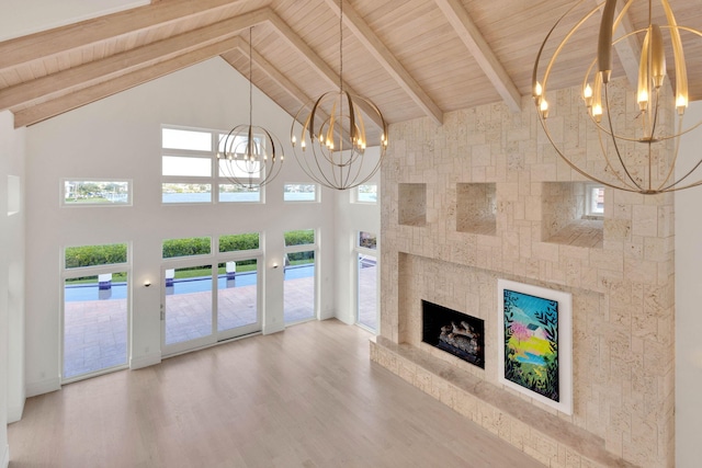 unfurnished living room with a chandelier, a tile fireplace, light hardwood / wood-style floors, and high vaulted ceiling