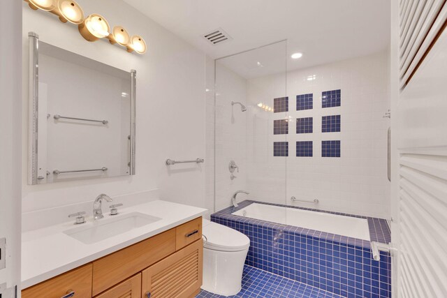 full bathroom with tiled shower / bath, toilet, tile floors, and vanity