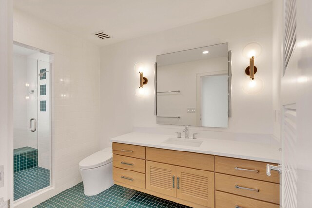 bathroom with toilet, tile flooring, a shower with shower door, and vanity