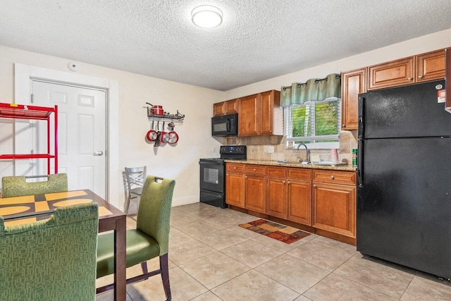 kitchen featuring light tile patterned floors, light stone countertops, a textured ceiling, black appliances, and sink