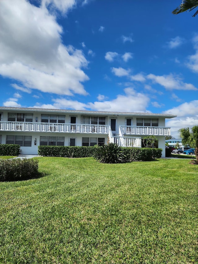 view of front of home with a balcony and a front lawn