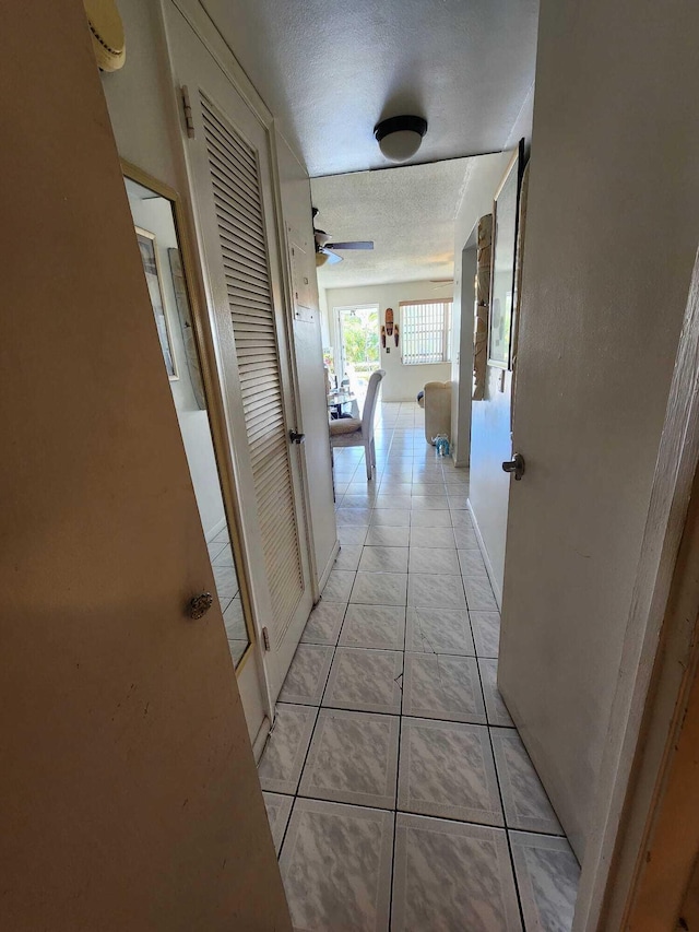 hall featuring light tile floors and a textured ceiling