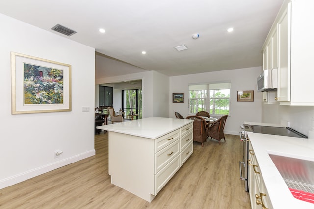 kitchen featuring white cabinets, light hardwood / wood-style floors, a center island, and stainless steel electric stove