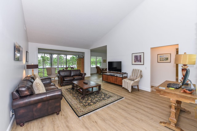 living room featuring high vaulted ceiling and light hardwood / wood-style floors