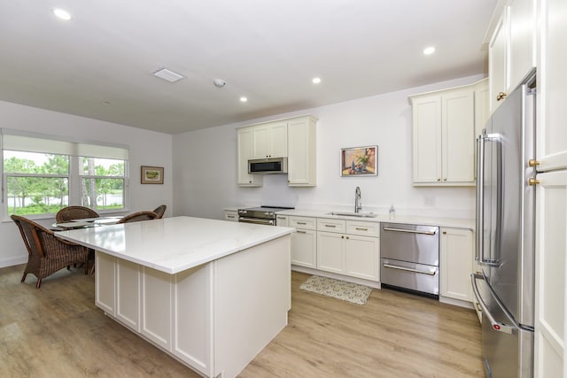 kitchen featuring sink, a kitchen island, white cabinets, and appliances with stainless steel finishes