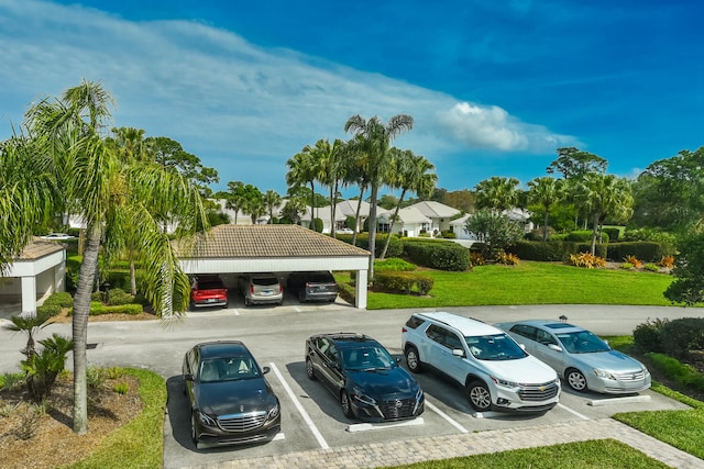 view of parking / parking lot with a yard and a carport