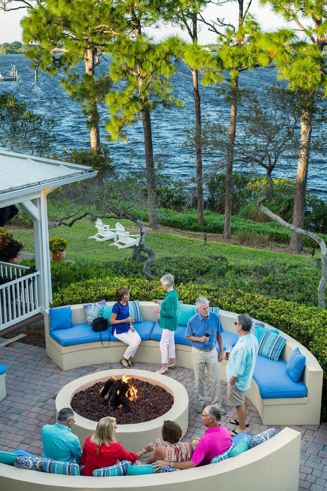 exterior space featuring an outdoor living space with a fire pit, a water view, and a patio area