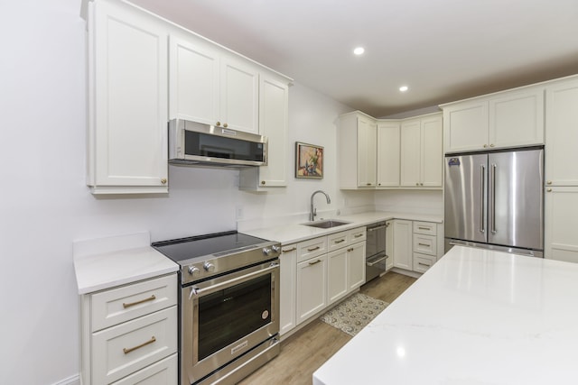 kitchen featuring sink, white cabinetry, light hardwood / wood-style floors, and appliances with stainless steel finishes