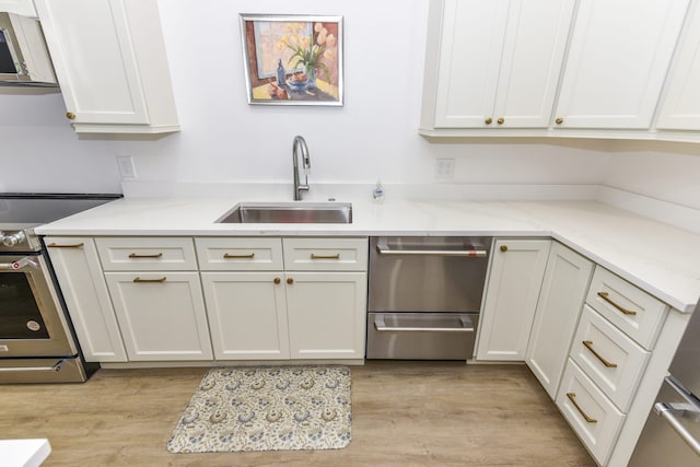 kitchen featuring sink, white cabinets, light hardwood / wood-style flooring, and appliances with stainless steel finishes