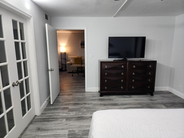 bedroom with wood-type flooring, a textured ceiling, and french doors