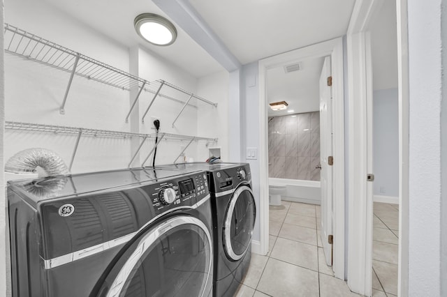 laundry area with separate washer and dryer and light tile patterned floors