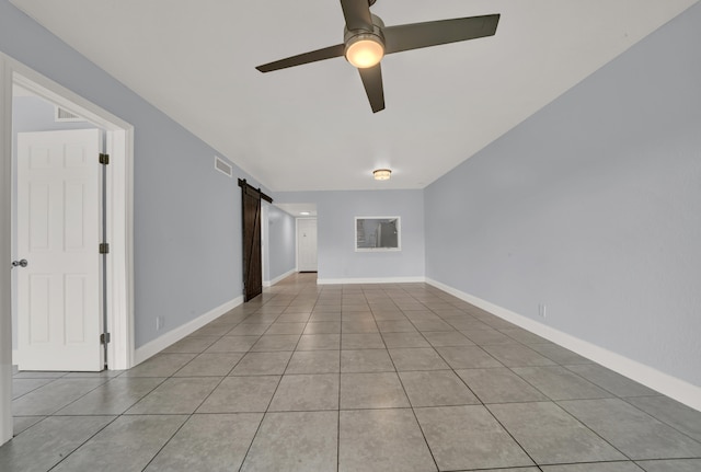 tiled empty room with a barn door and ceiling fan