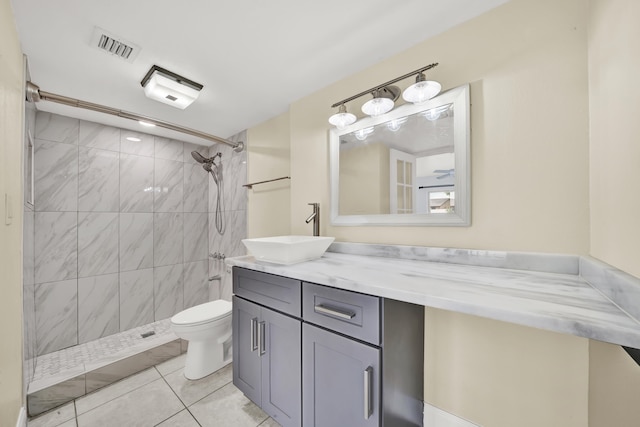 bathroom featuring a tile shower, tile patterned flooring, vanity, and toilet