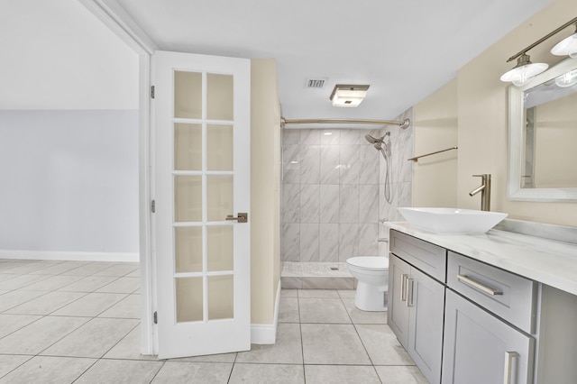 bathroom with tile patterned flooring, vanity, toilet, and tiled shower