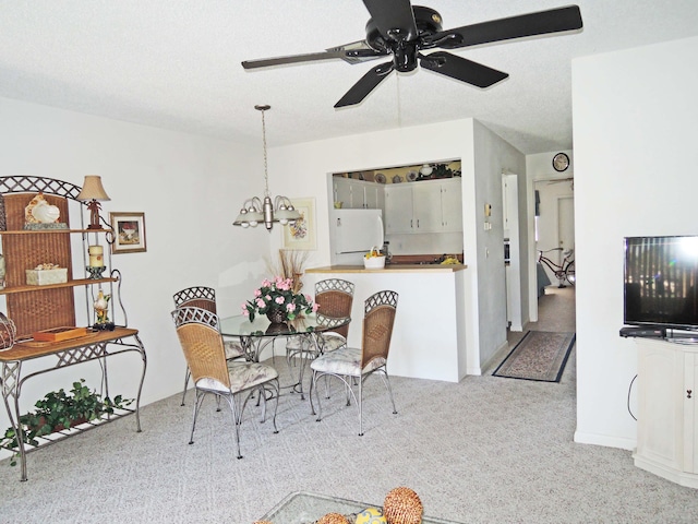 carpeted dining area with ceiling fan with notable chandelier