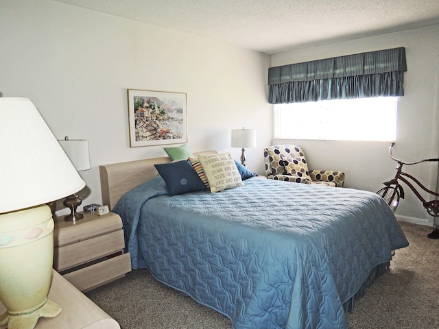 bedroom with a textured ceiling and dark carpet