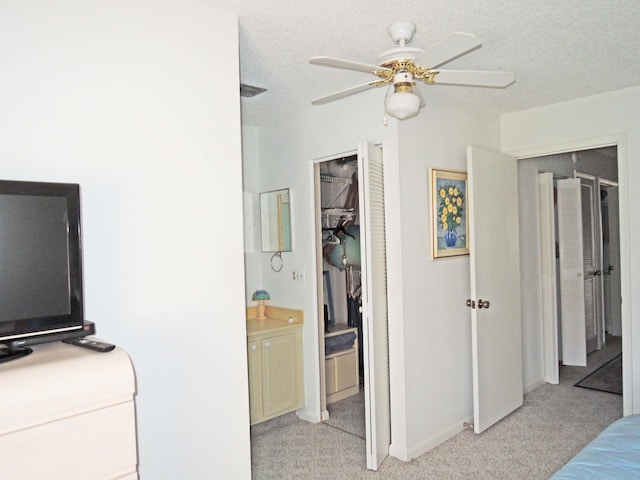 bedroom featuring ensuite bath, light colored carpet, and ceiling fan