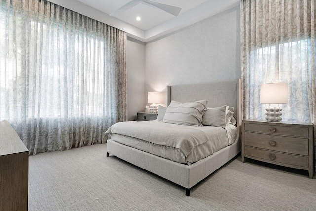 carpeted bedroom featuring multiple windows and ceiling fan