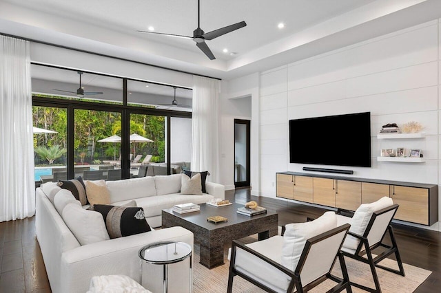 living room featuring ceiling fan, a tray ceiling, and dark hardwood / wood-style floors