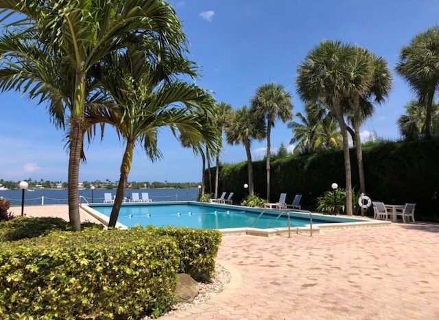 view of swimming pool with a patio area and a water view